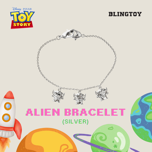 A silver-tone Alien bracelet featuring three dangling Alien figures on a delicate chain, presented on a beige background with Toy Story branding, planets, and a rocket illustration.
