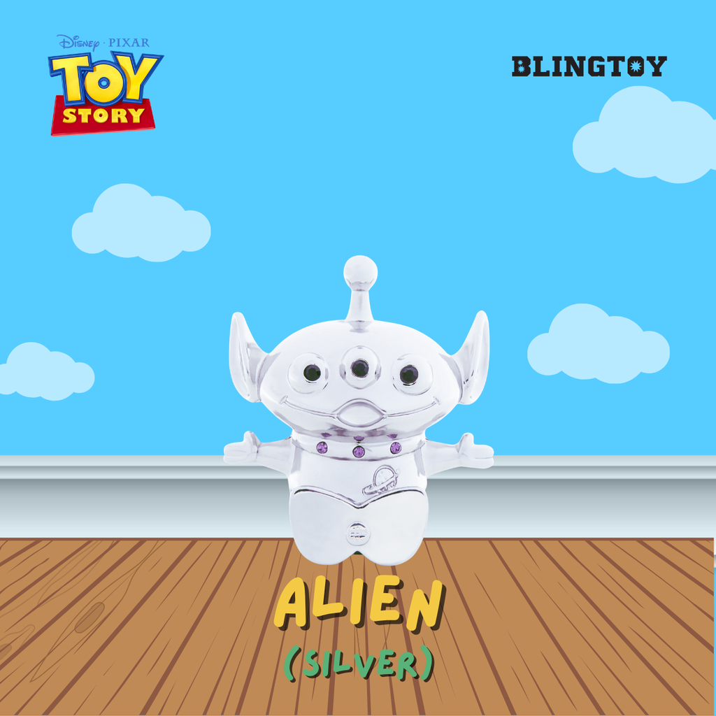 A silver Disney Pixar Toy Story Alien plush toy centered against a blue sky and clouds background with a wooden floor. Visible text includes Disney Pixar Toy Story, BLINGTOY, and ALIEN (SILVER).