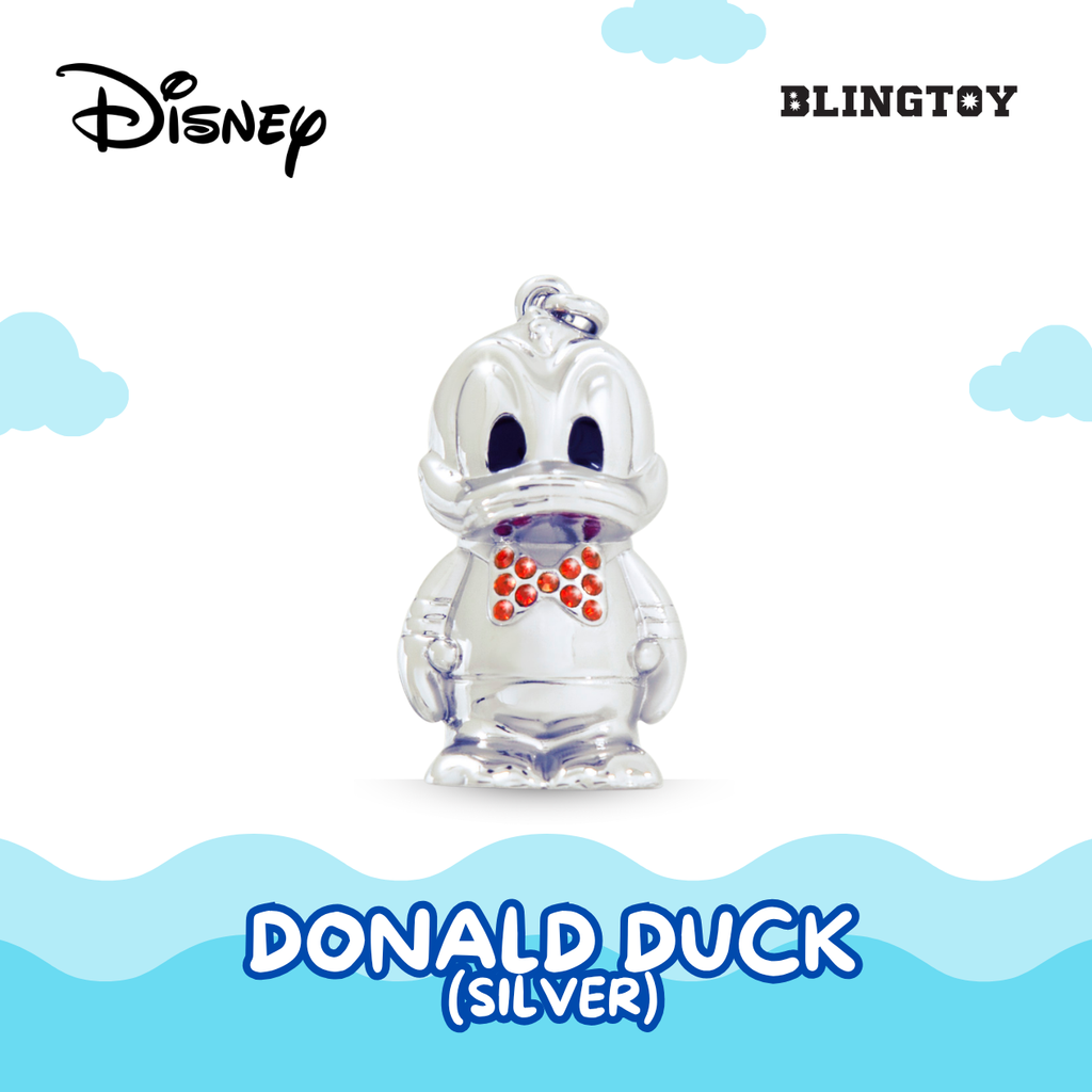 A silver Donald Duck charm pendant with a red polka-dot bow tie, shown against a white background with light blue clouds and wavy lines. The Disney and BLINGTOY logos are visible in the top corners, and 'DONALD DUCK (SILVER)' is written at the bottom.