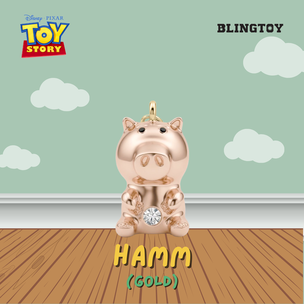 A gold-plated Hamm toy pendant from Disney Pixar Toy Story, shown sitting on a wooden floor against a mint green wall with clouds. The image includes 'BLINGTOY' branding and 'HAMM (GOLD)' text.