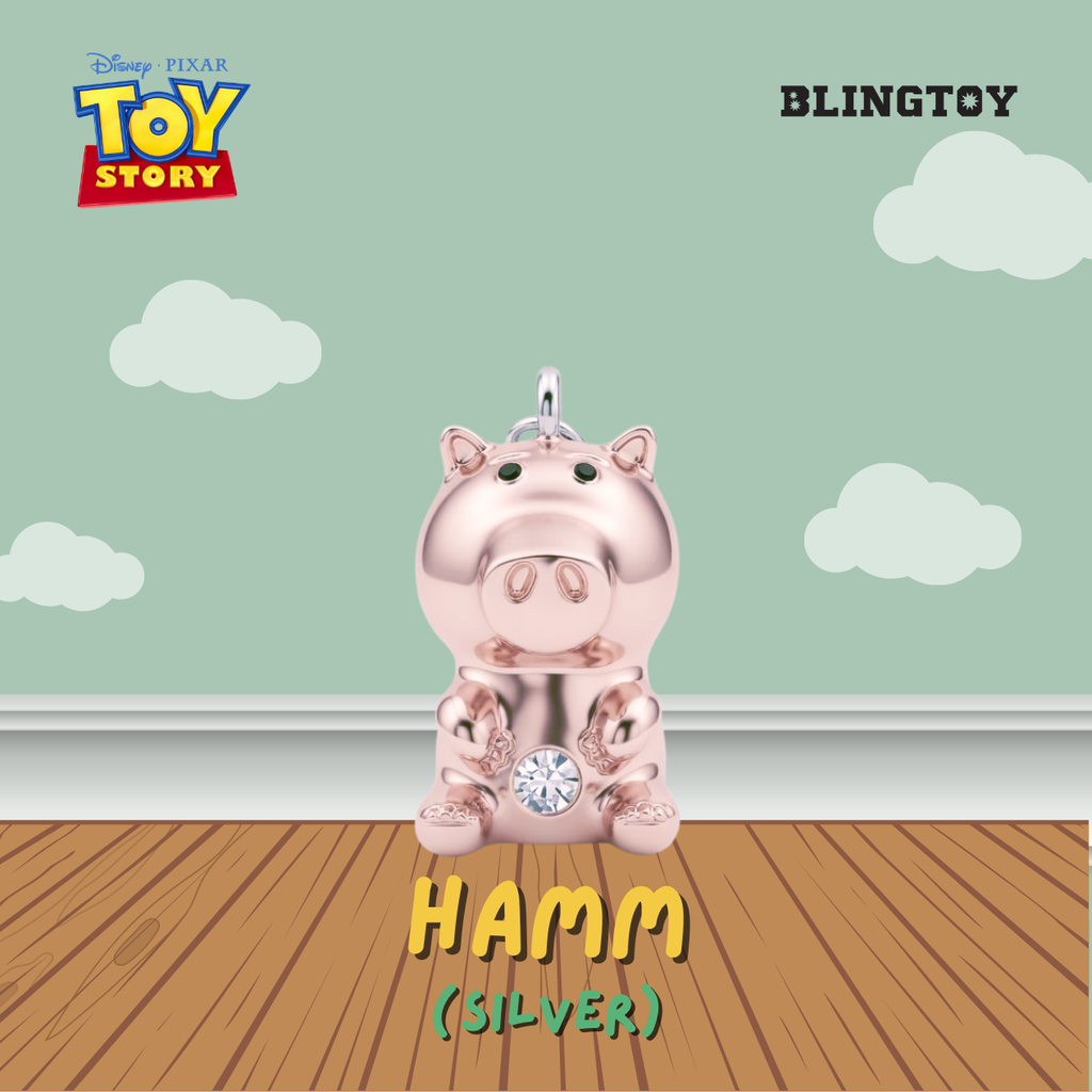 A metallic silver pig-shaped charm pendant inspired by Disney Pixar's Toy Story, featuring a small crystal gem on its belly, shown against a stylized background with a light green sky, white clouds, and a wooden floor. Text overlays include 'BLINGTOY', 'HAMM (SILVER)', and the Toy Story logo.