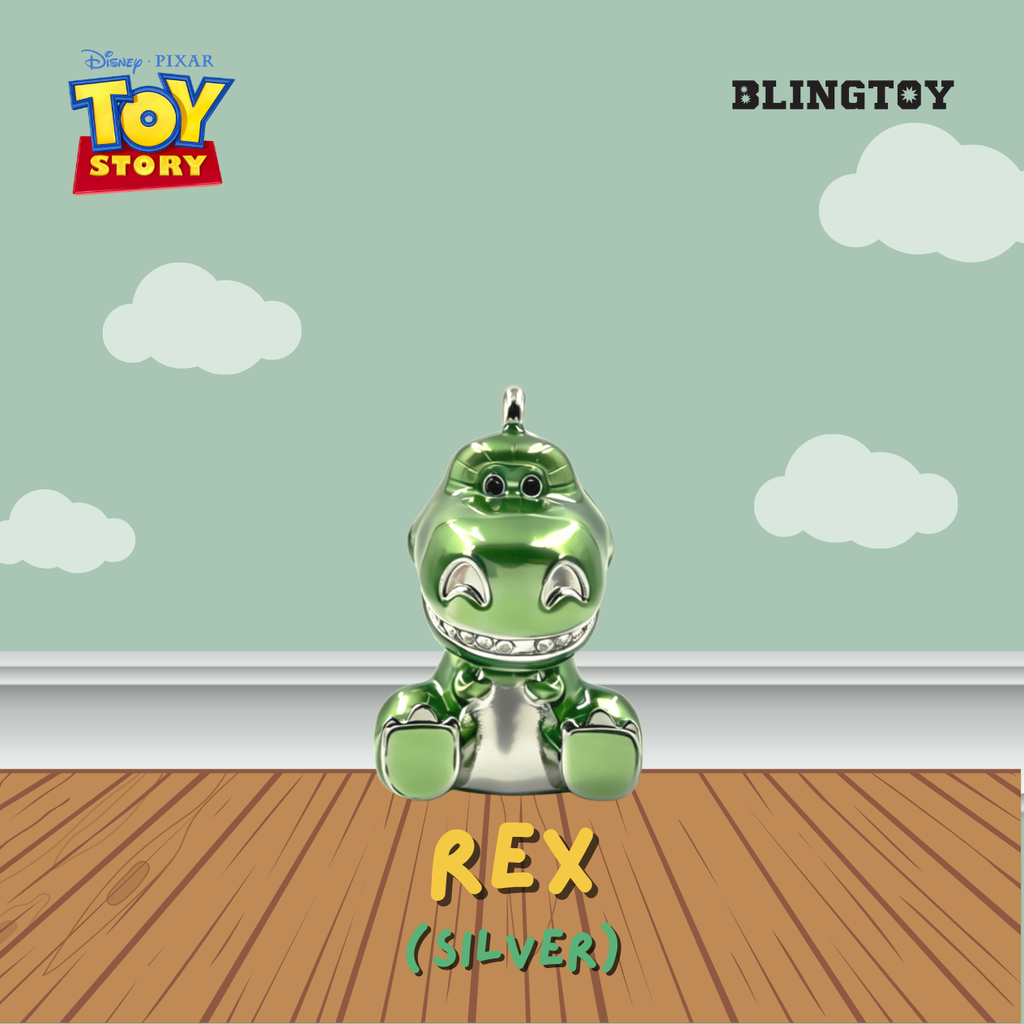 A metallic silver and green Rex dinosaur ornament from Disney Pixar Toy Story, displayed on a wooden floor against a light green wall with white clouds. The image features the 'BLINGTOY' brand logo in the top right and the 'Disney Pixar Toy Story' logo in the top left.